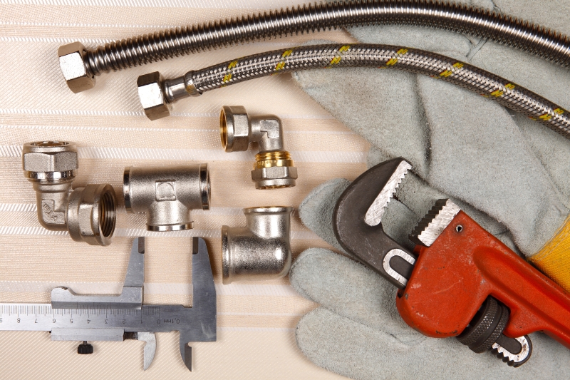 Plumber working on pipes in a Acton home